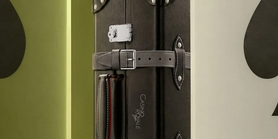 Valise noire avec boucle et inscription Casino Royale sur fond vert.
