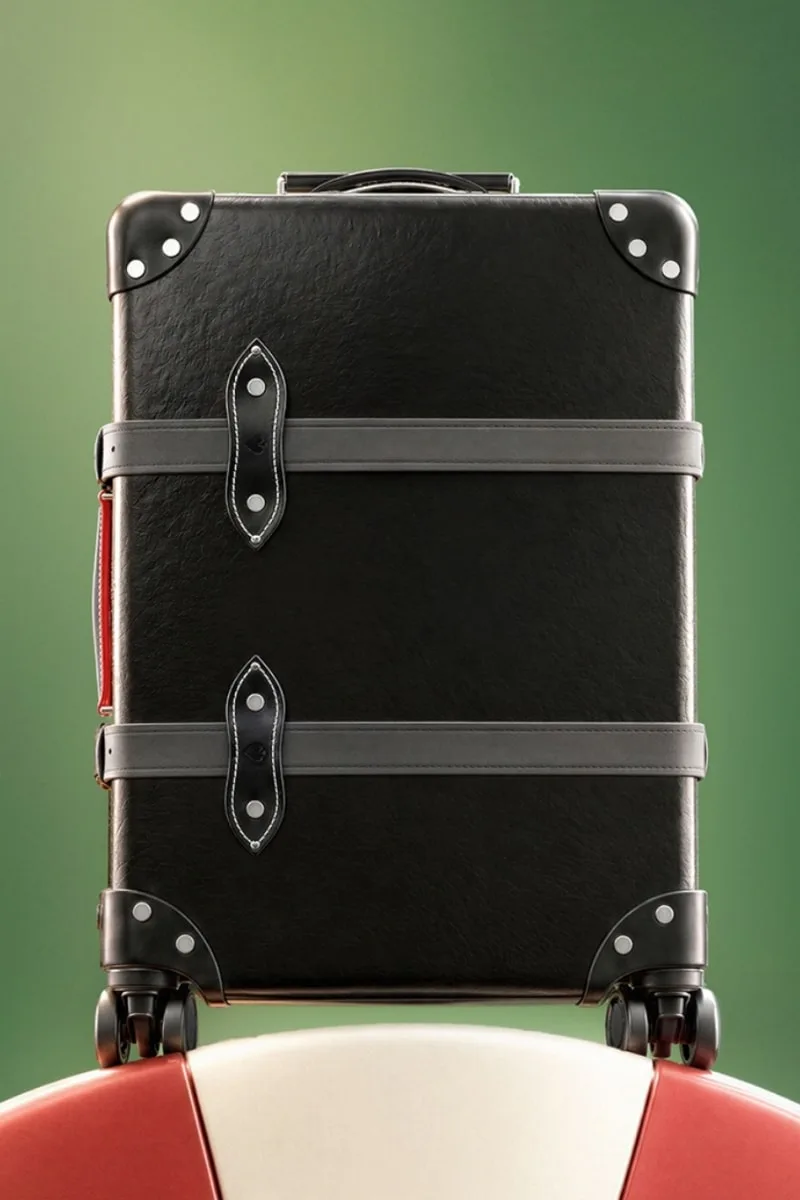 Valise noire sur fond vert et rouge, design élégant et moderne.