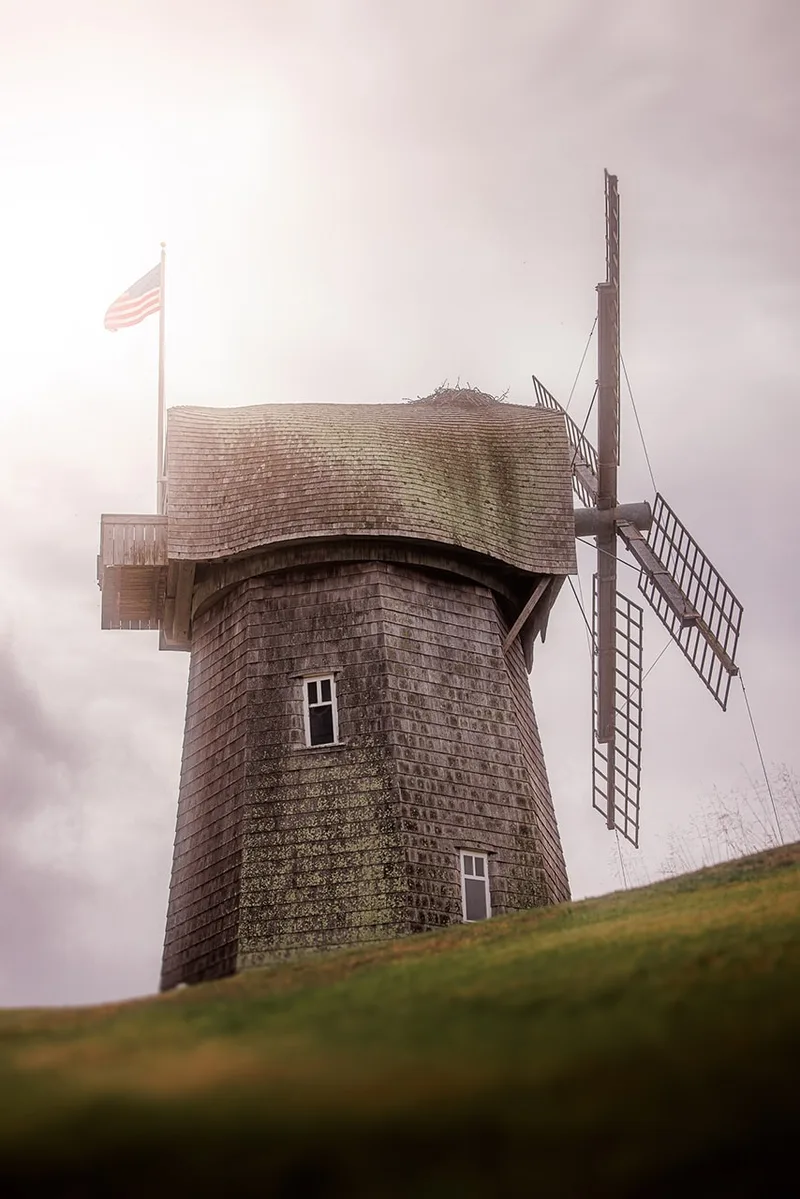 Vieux moulin à vent avec drapeau américain à côté.