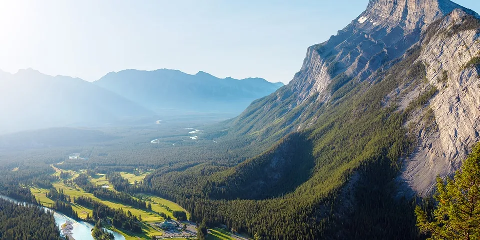 Vallée verdoyante traversée par une rivière, au pied de hautes montagnes