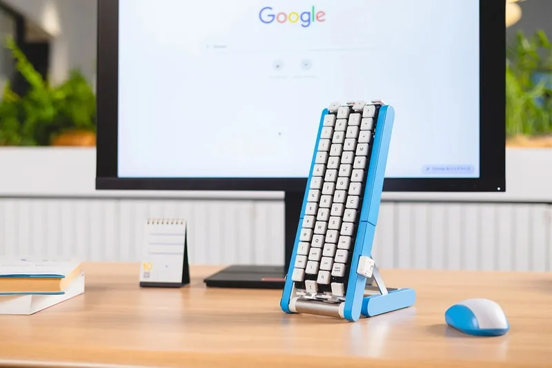 Clavier vertical bleu devant un écran d'ordinateur avec Google affiché.