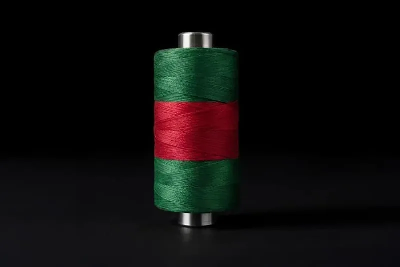 Bobine de fil avec bandes verte et rouge, fond noir