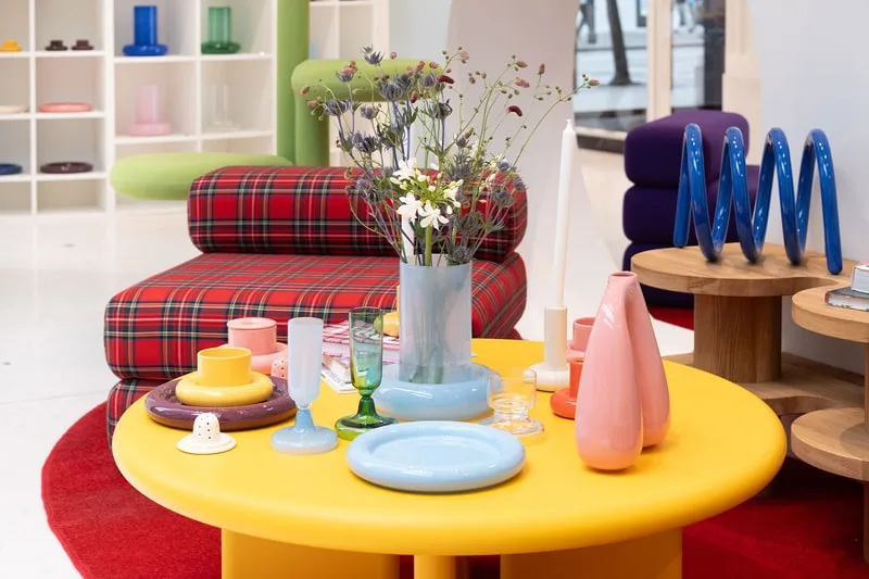 Salon moderne avec mobilier coloré et décoration florale.