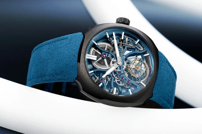 Montre avec mécanisme visible, bracelet bleu sur fond flou.