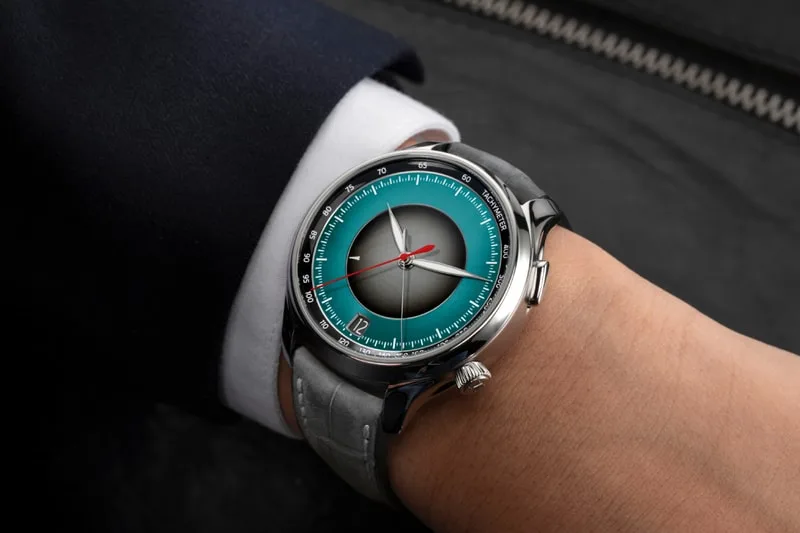 Montre élégante avec cadran bicolore et aiguilles rouges.
