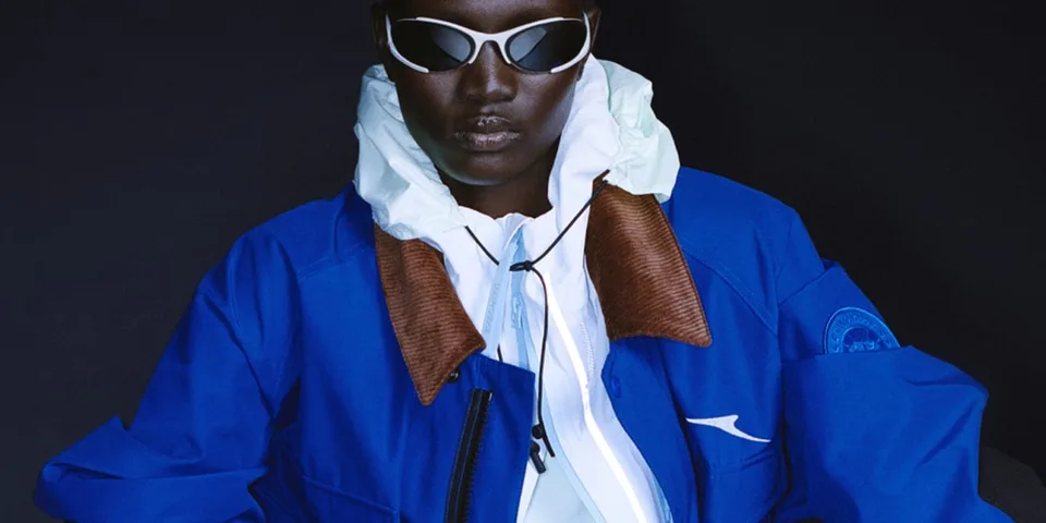 Personne portant des lunettes et une veste bleue sur fond sombre.