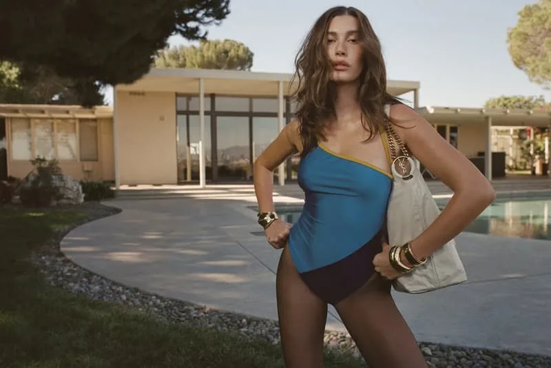 Femme en maillot de bain devant une maison moderne avec piscine.