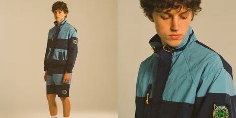 Homme en tenue sportive bleue et brune avec logo, regardant vers le bas.