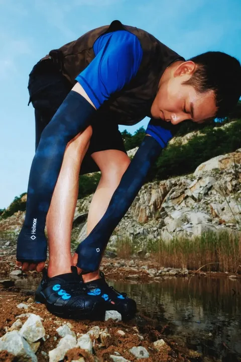 Homme en tenue de sport près d'un plan d'eau et de rochers, journée ensoleillée.