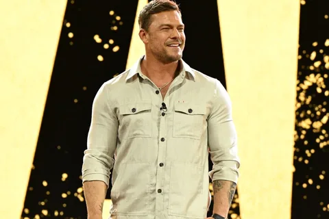Homme souriant en chemise claire sur fond jaune et noir.