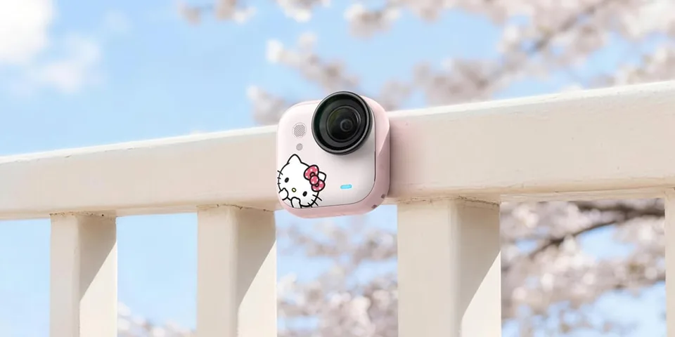 Caméra avec design Hello Kitty sur une balustrade, arrière-plan flou avec fleurs de cerisier.