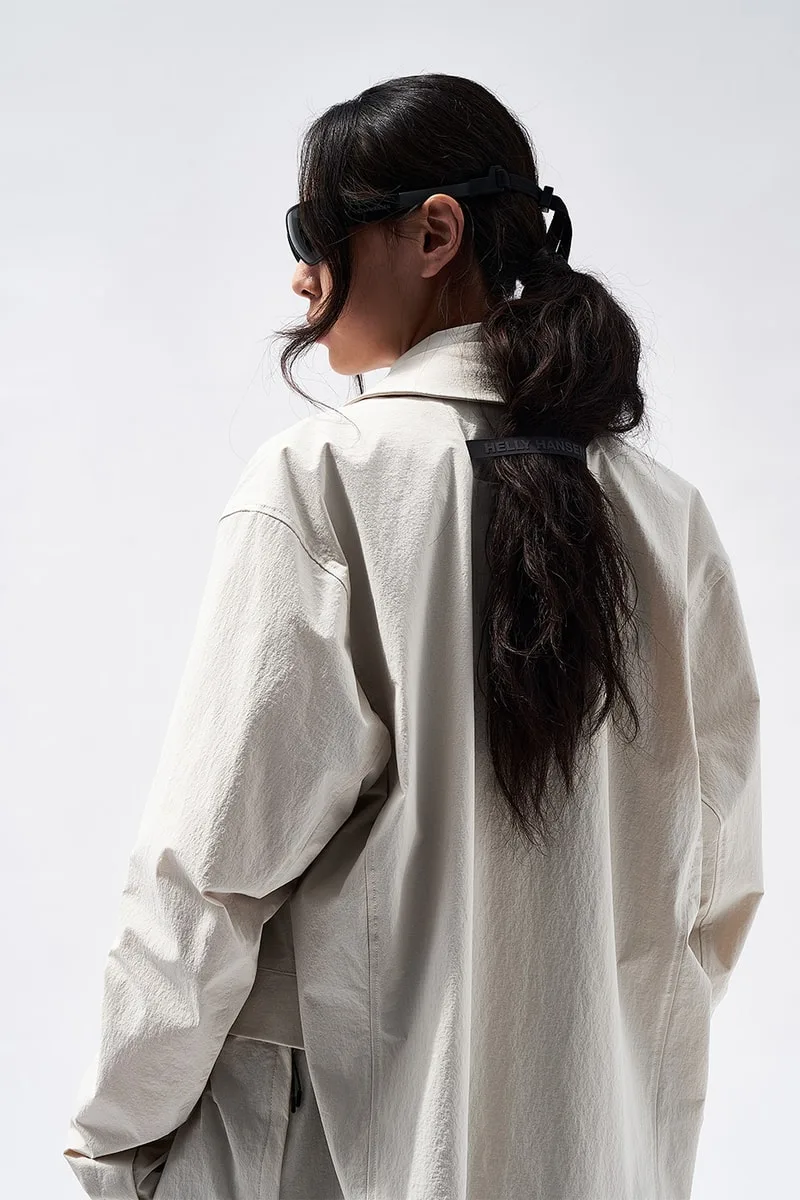 Personne en manteau beige avec des lunettes de soleil, vue de dos.