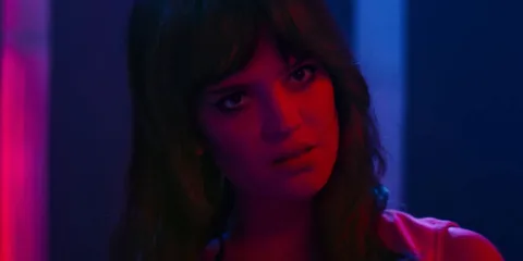 Femme avec éclairage rouge et bleu, regard intense.