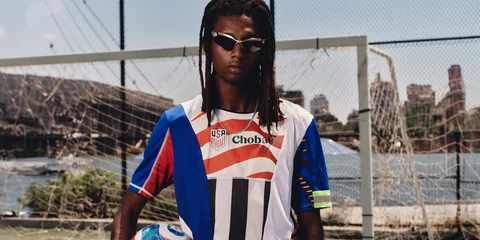 Jeune homme en tenue sportive devant un but de football.