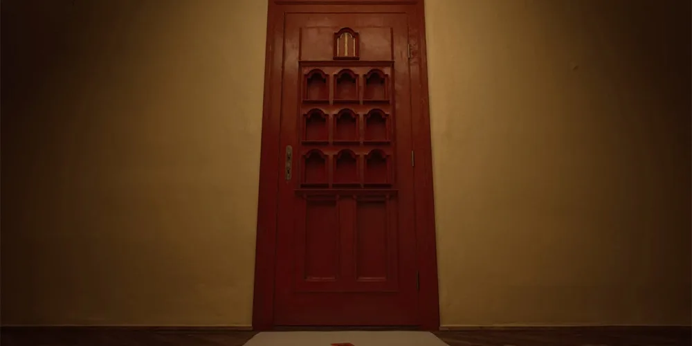 Porte rouge en bois dans une pièce sombre avec lumière tamisée.