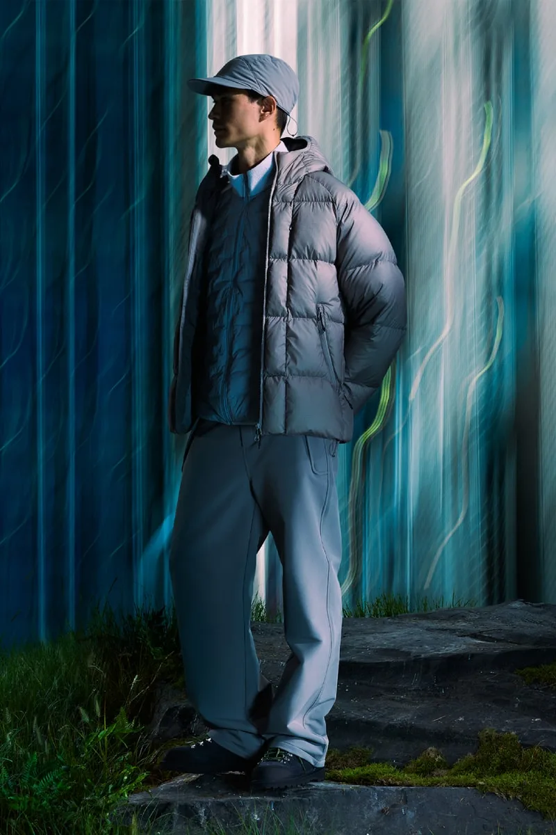 Homme en manteau matelassé gris dans un décor abstrait lumineux.