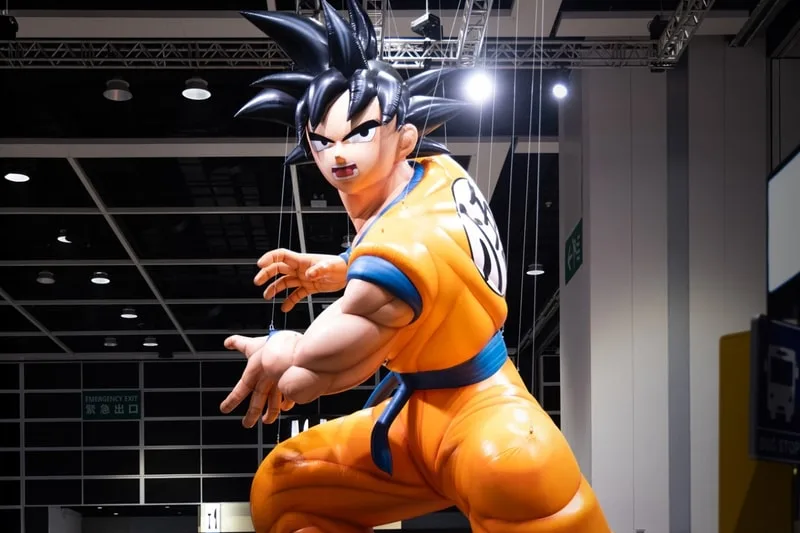 Grande figurine animée en costume orange avec des cheveux noirs hérissés.