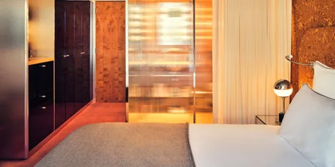 Chambre d'hôtel moderne avec lit, lumières et portes coulissantes en verre.