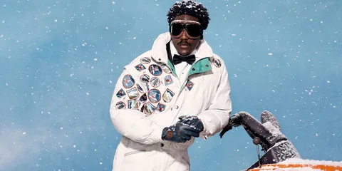 Homme en tenue de ski blanche et lunettes, sous une chute de neige.