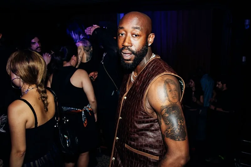 Homme avec tatouage dans une fête, arrière-plan flou.