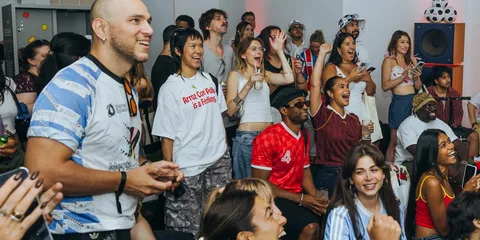 Groupe de personnes souriantes lors d'un événement social intérieur, applaudissant.