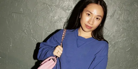 Personne portant un sweat bleu avec un sac rose.