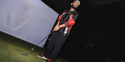 Homme avec club de golf dans un simulateur intérieur.