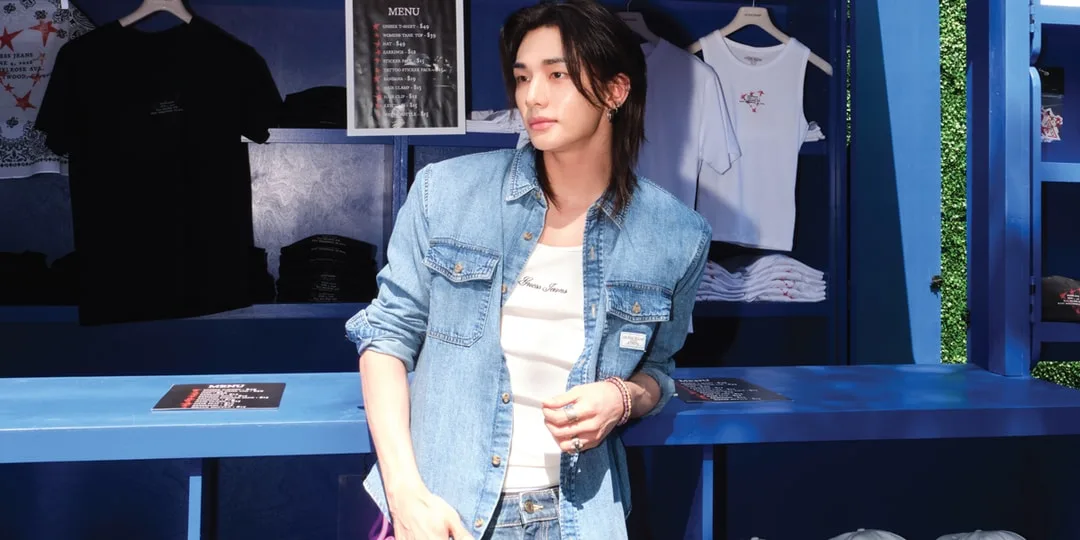 Homme en tenue denim devant des t-shirts exposés sur étagères bleues.