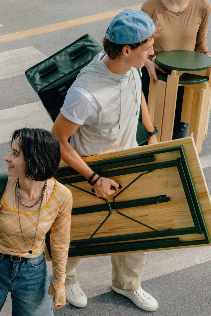 Jeunes transportant des meubles et des sacs dans la rue.