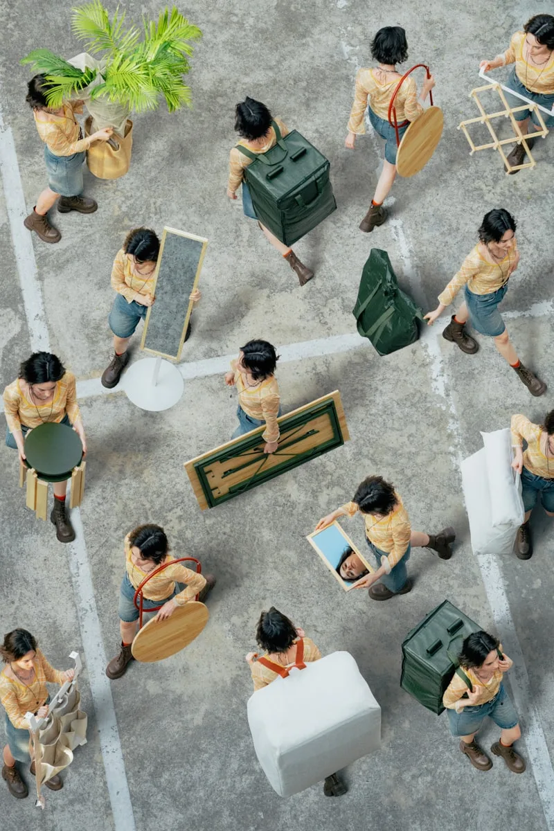 Nombreuses personnes portant divers objets dans un espace urbain.