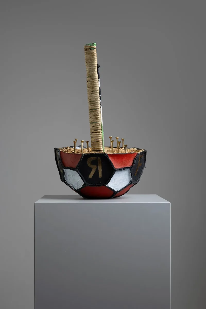 Sculpture avec un ballon de foot et manche entouré de corde.