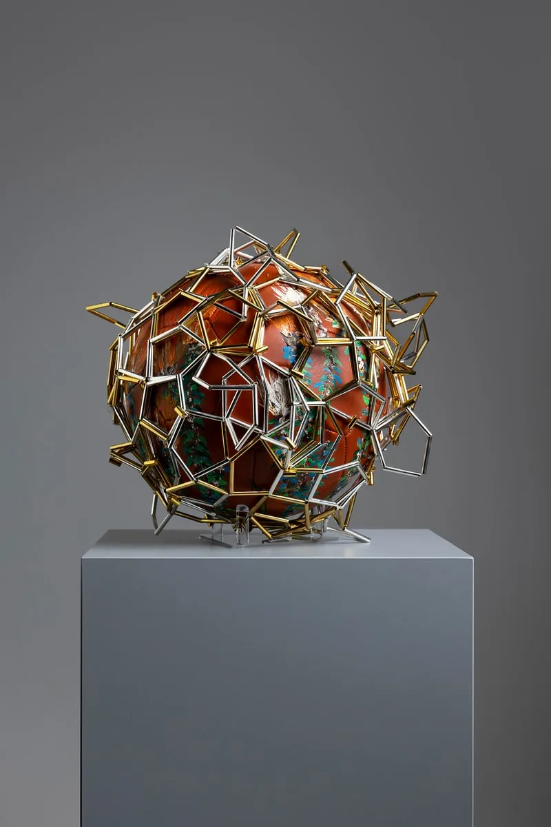 Sculpture géométrique colorée sur un socle gris.