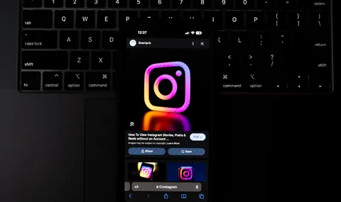 Téléphone avec logo Instagram lumineux sur clavier d'ordinateur, écran allumé.