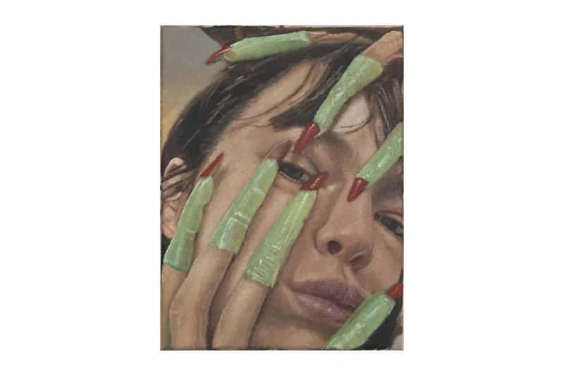 Femme avec des doigts artificiels verts et longs ongles rouges au visage.