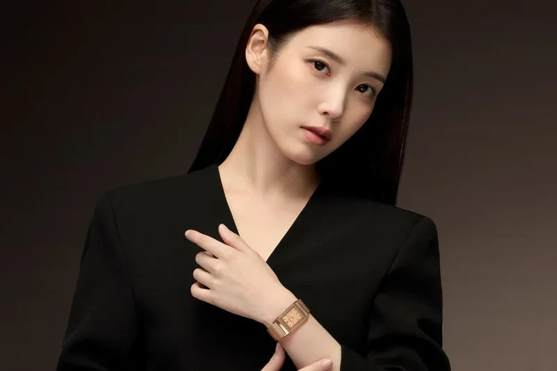 Femme élégante portant une montre-bracelet dorée, vêtue de noir.