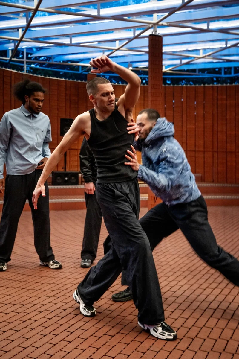 Danseurs en mouvement dans un espace moderne avec un plafond en verre.