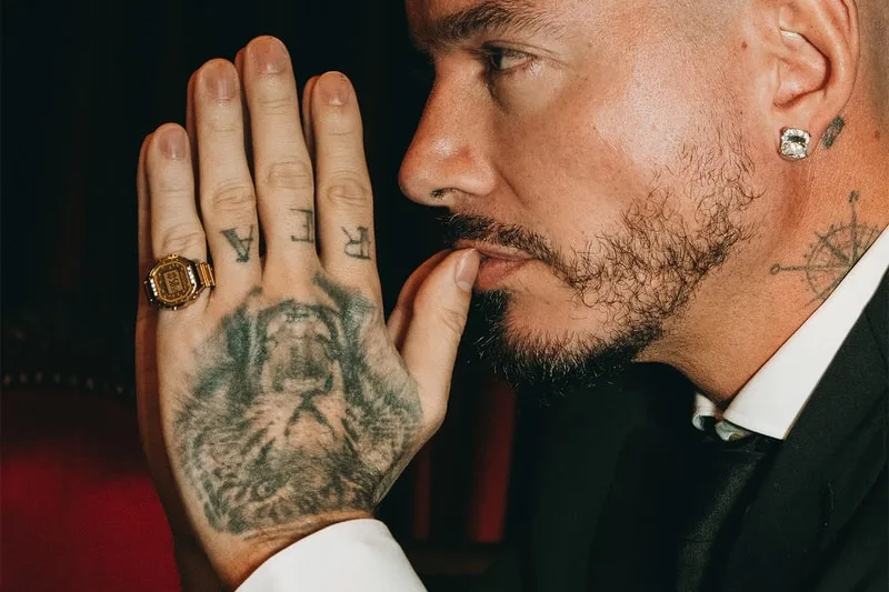 Homme en costume avec tatouages et bijoux, profil droit