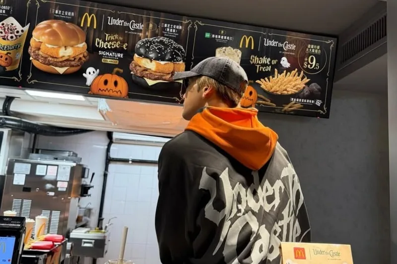 Personne portant une veste devant un menu de fast-food avec décorations d'Halloween.