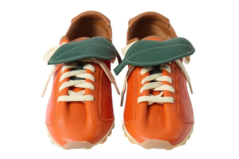Chaussures orange avec lacets beige et languette verte.