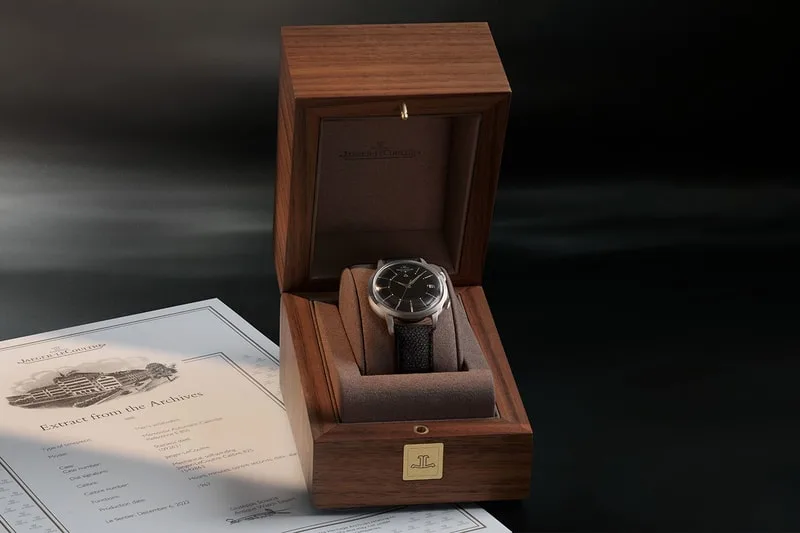 Montre dans un coffret en bois avec document à côté.