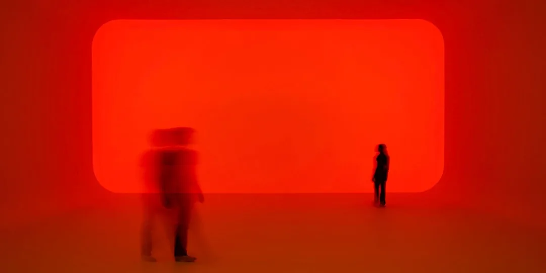 Salle lumineuse rouge avec silhouettes floues de personnes.