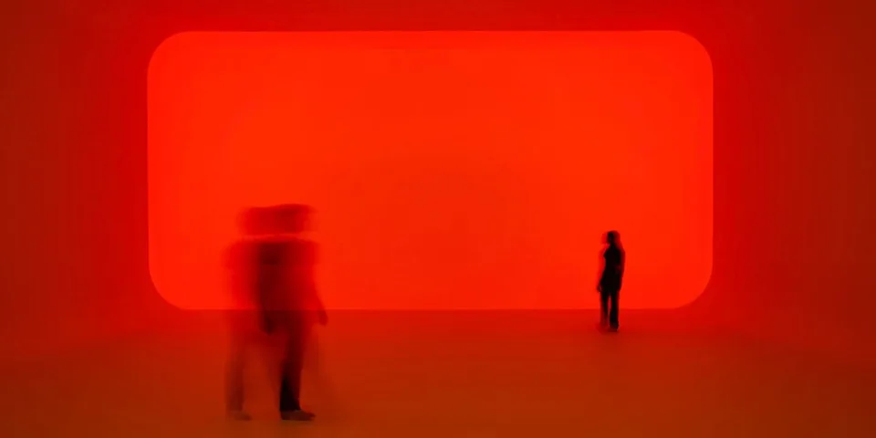Salle lumineuse rouge avec silhouettes floues de personnes.