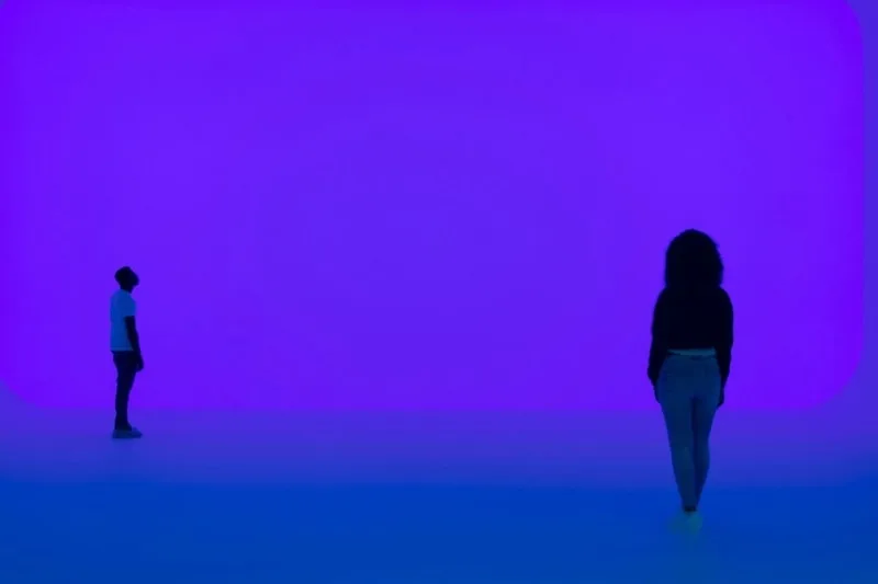 Deux personnes éloignées dans un espace violet lumineux.