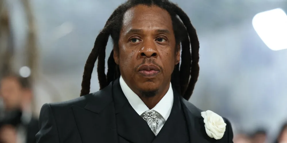 Homme aux cheveux longs en costume sombre avec rose blanche