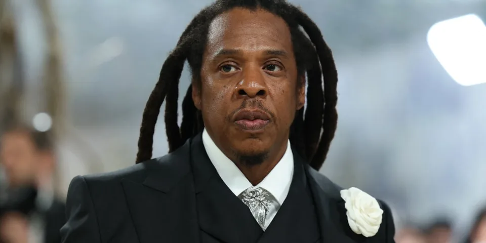 Homme aux cheveux longs en costume sombre avec rose blanche