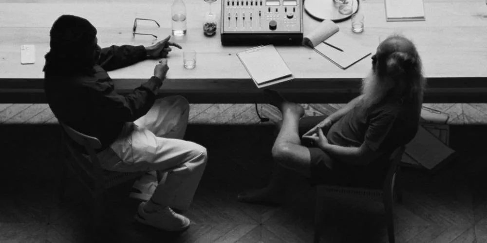 Deux personnes assises à une table avec des livres et un appareil.