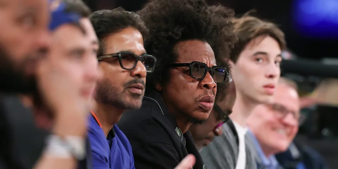Groupe de personnes regardant un match de basketball assises près du terrain.