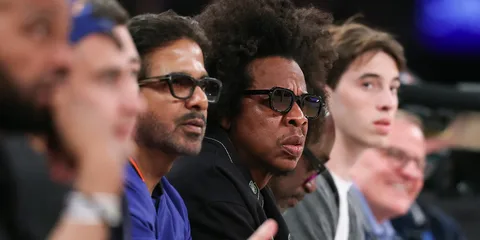 Groupe de personnes regardant un match de basketball assises près du terrain.