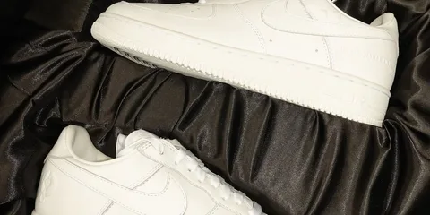 Deux baskets blanches sur un tissu noir.