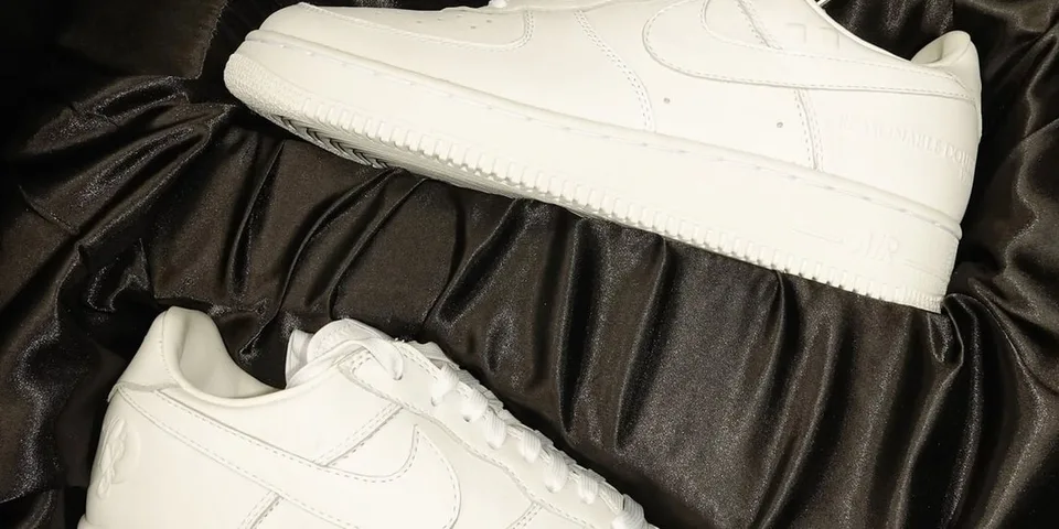 Deux baskets blanches sur un tissu noir.